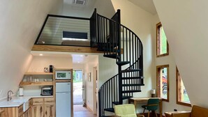 En moderne lejlighed i loftstil med køkken, opholdsstue og en spiraltrappe.