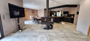 A modern kitchen with a central island, a dining area with a table and chairs, and a TV mounted on the wall. - Modern villa with swimming pool (Vézénobres)