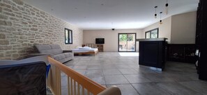 A spacious living room with a stone wall, a sofa, a TV, and a fireplace.