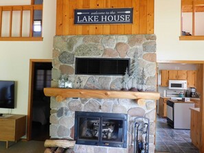 A stone fireplace with a sign above it that reads "welcome to the LAKE HOUSE."