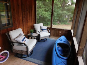 A covered porch with wicker chairs, a blue sofa, and a pink bicycle.