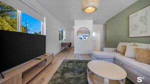 Un salon moderne avec un téléviseur à écran plat, une table basse ronde, un canapé et un luminaire suspendu.
