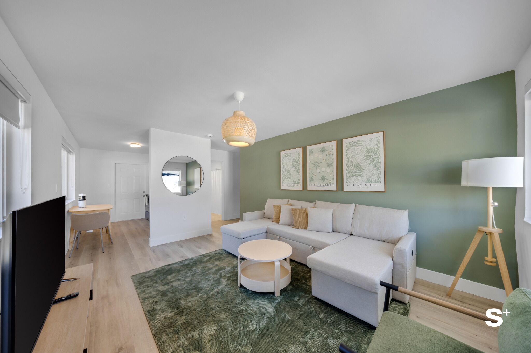 A modern living room with a white sectional sofa, a round coffee table, a TV, and a lamp.
