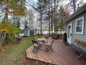 A deck with a table and chairs, a grill, and a small shed. - Long Lake Waterfront Cabin: Family Fun (Longville)