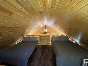 A cozy attic bedroom with two beds, wooden walls, and a central light fixture. - Long Lake Waterfront Cabin: Family Fun (Longville)