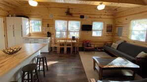 Interior de una cabaña de madera con cocina, comedor y sala de estar.