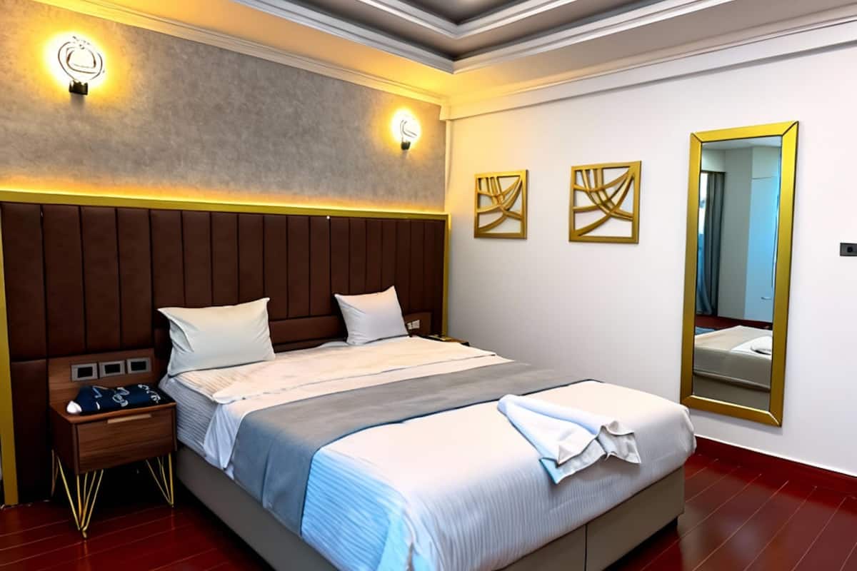 A modern hotel room with a large bed, bedside tables, and a mirror.