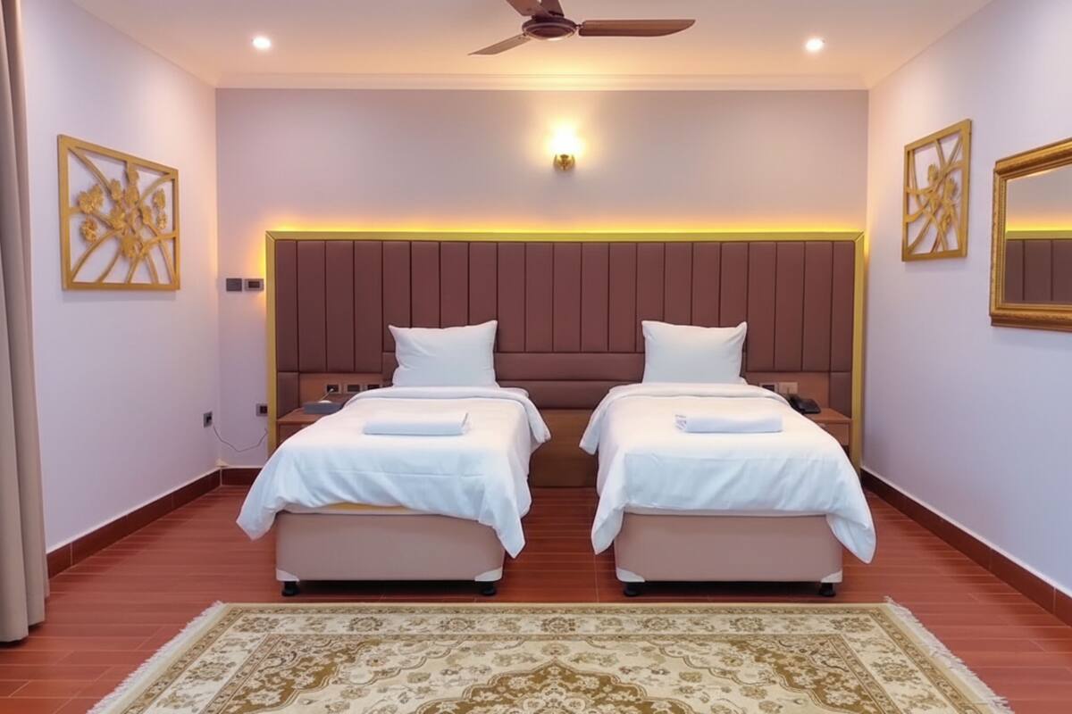 A hotel room with two beds, a ceiling fan, a nightstand, and a decorative wall piece.