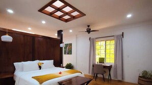 Ein modernes Schlafzimmer mit Bett, Nachttisch, Deckenventilator und einem Fenster mit Vorhängen.