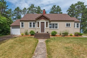 A two-story house with a front entrance, a garage, and a well-maintained lawn. - Upper Hay Pet Friendly Getaway Home (Pequot Lakes)