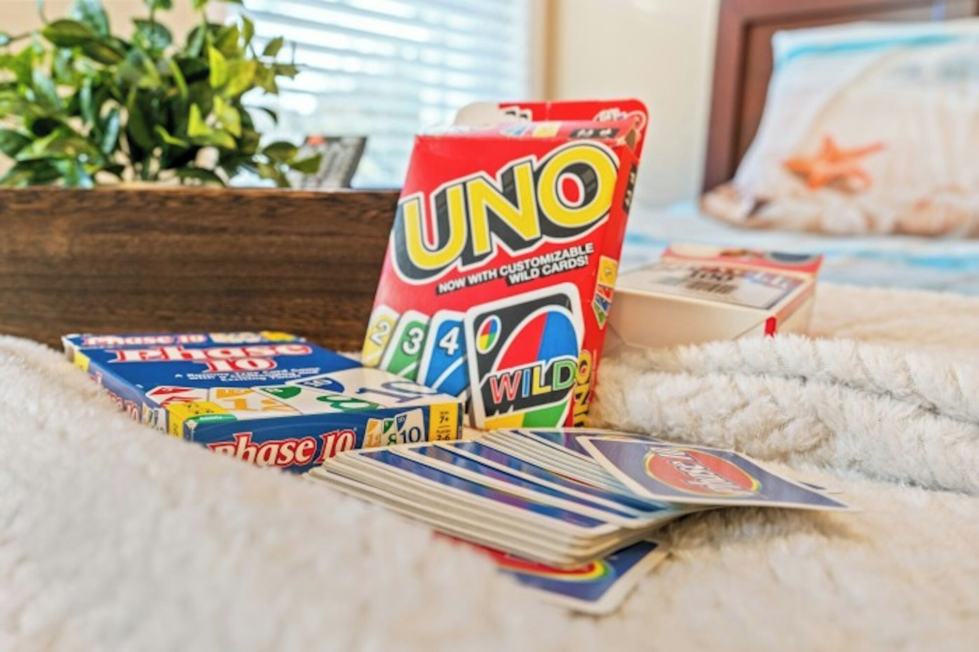Una caja del juego UNO, una baraja de cartas de UNO y una caja del juego Monopoly sobre una superficie mullida.