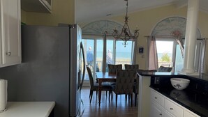 A kitchen with a view of the ocean, a dining area with chairs and a table, and a chandelier. - Oceanfront Tybee Island, a spacious home perfect for family vacations. (Tybee Island)