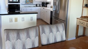 A modern kitchen with white cabinets, a stainless steel refrigerator, a microwave, and a coffee maker. - Oceanfront Tybee Island, a spacious home perfect for family vacations. (Tybee Island)
