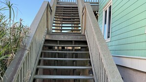 A wooden staircase leading to a building with a green exterior. - Oceanfront Tybee Island, a spacious home perfect for family vacations. (Tybee Island)