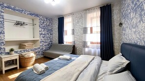 Un dormitorio con una cama, una silla, una mesita de noche con una cesta y un espejo.