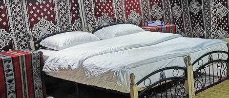 A bed with a metal frame, white bedding, and patterned curtains.