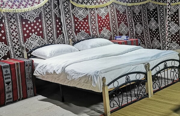 A bed with a metal frame, white bedding, and patterned curtains.