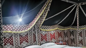 Una habitación tipo tienda de campaña con una cama, almohadas y una pequeña mesa.