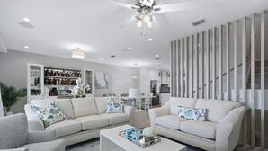A modern living room with a sectional sofa, a coffee table, and a built-in bar area with shelves of bottles. - Azure Key Escape - Waterfront Retreat w/ Pool, Dock & Balconies (Marathon)