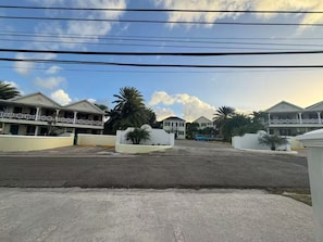 A row of white buildings with balconies, palm trees, and a clear sky. - The Palms apt 1 (Cedar Grove)
