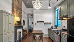 Een keuken met houten vloeren, een kroonluchter en een bakstenen muur.