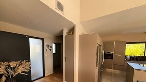 A modern kitchen with stainless steel appliances, a wooden floor, and a view of greenery outside. - Uzès, in a quiet, sought-after area, contemporary villa with swimming pool (Uzès)