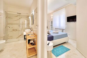 Ein modernes Badezimmer mit Duschkabine aus Glas, einem Waschbecken und einem Holzboden mit Handtüchern.