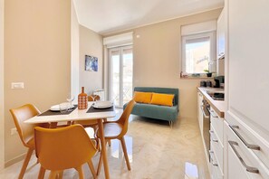 Ein Essbereich mit Tisch, Stühlen und einer Couch im Hintergrund.