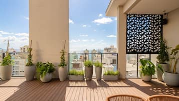 Un balcón con plantas en macetas, vista a la ciudad y una pared con diseño.