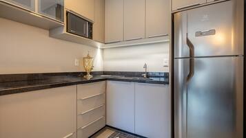 Una cocina moderna con un refrigerador de acero inoxidable, un microondas y un fregadero.