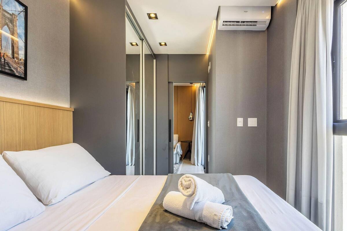 Een hotelkamer met een bed, een handdoek, een airconditioning en uitzicht op de gang.