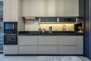 Eine moderne Küche mit Einbaugeräten, einer schwarzen Arbeitsplatte und einer Glasrückwand.