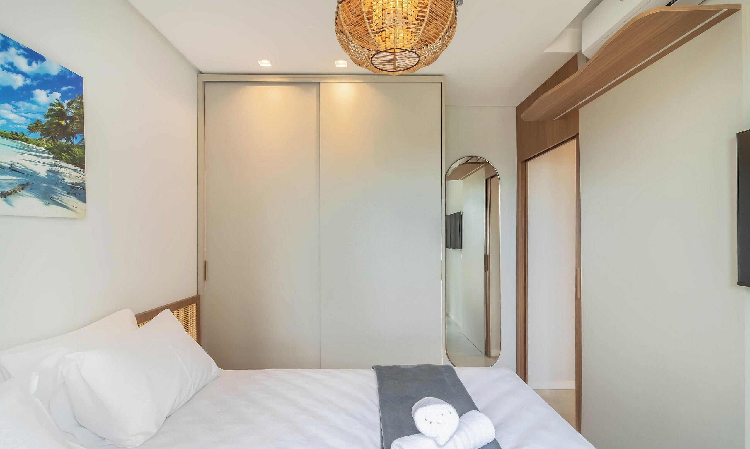 A bedroom with a bed, a large mirror, and a ceiling light fixture.