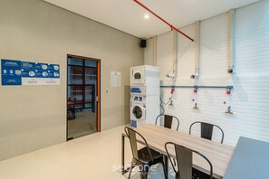 Eine moderne Küche mit integriertem Waschmaschine, einem Essbereich mit Stühlen und einer sichtbaren Wasserleitung an der Wand.