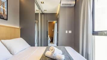 Une chambre d’hôtel avec un lit, un climatiseur fixé au mur et une fenêtre avec des rideaux.