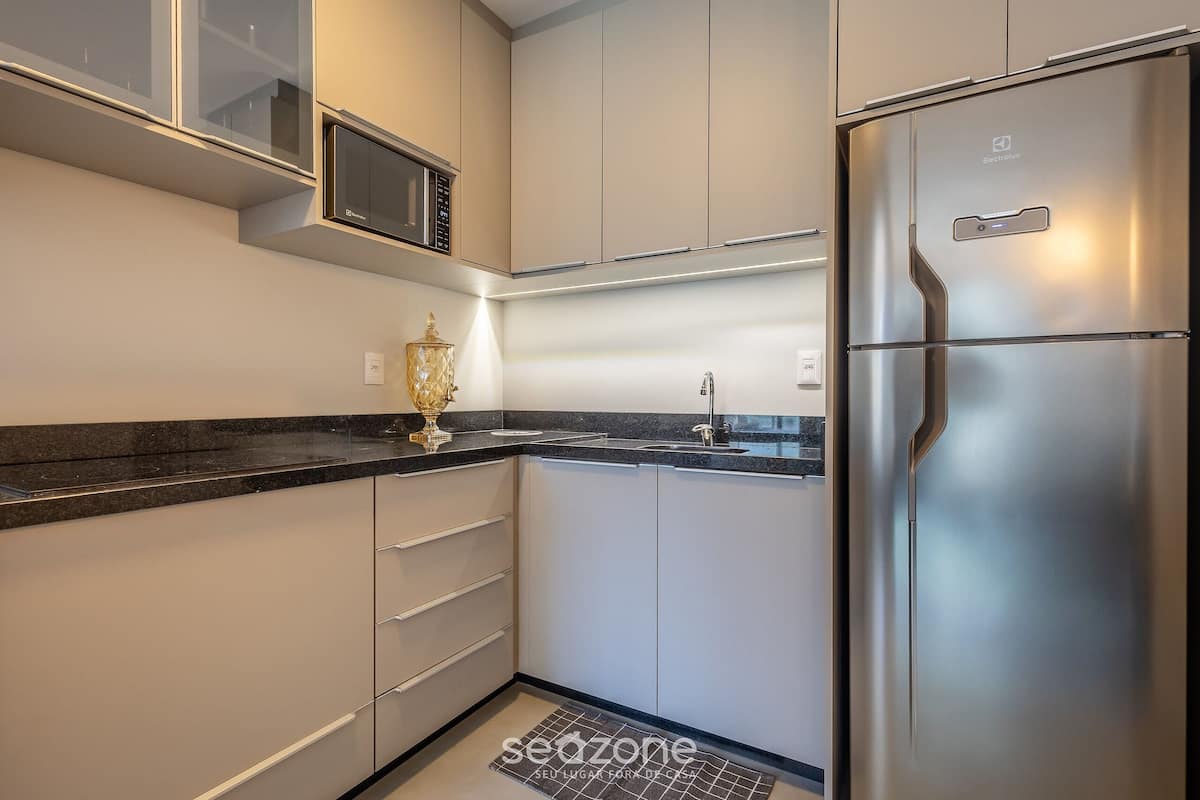 Een moderne keuken met een roestvrijstalen koelkast, een magnetron en een spoelbak.