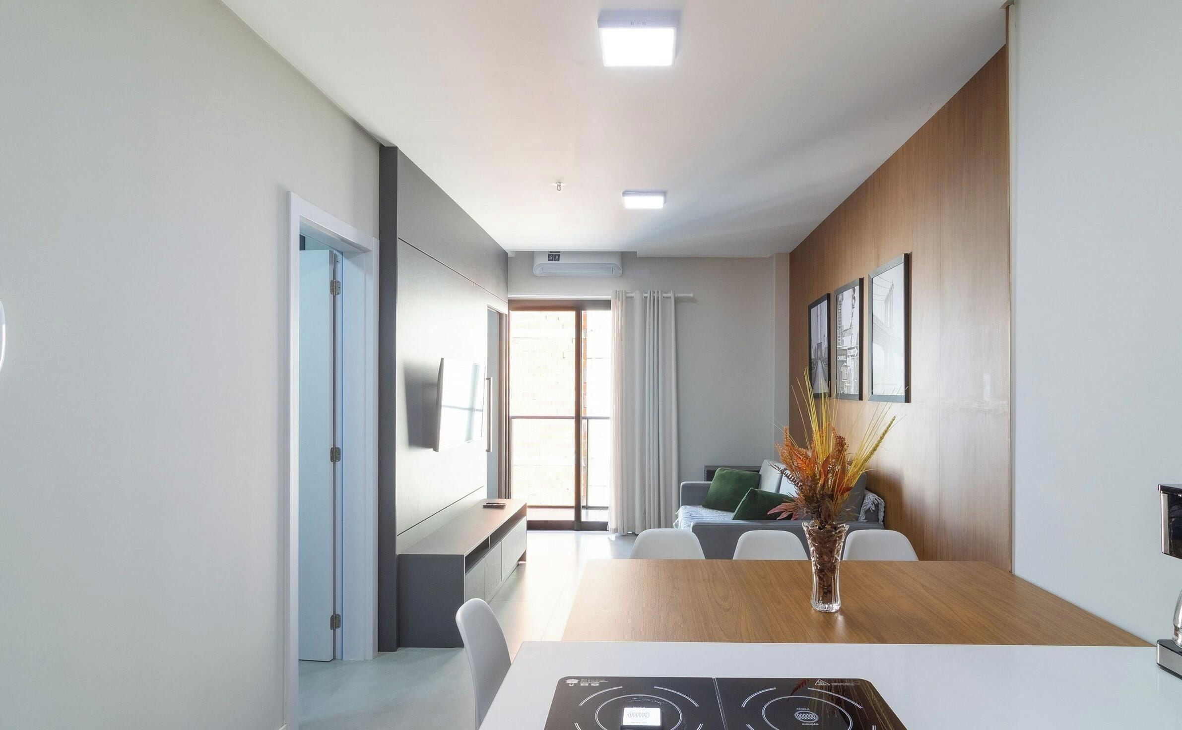 Habitación de hotel moderna con zona de comedor, un juego de sofá y un amplio ventanal con cortinas.