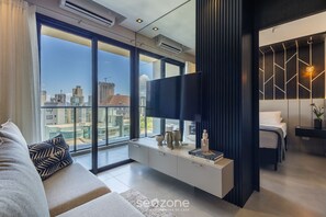 Une chambre moderne avec un grand lit, une télévision et une vue sur la ville.