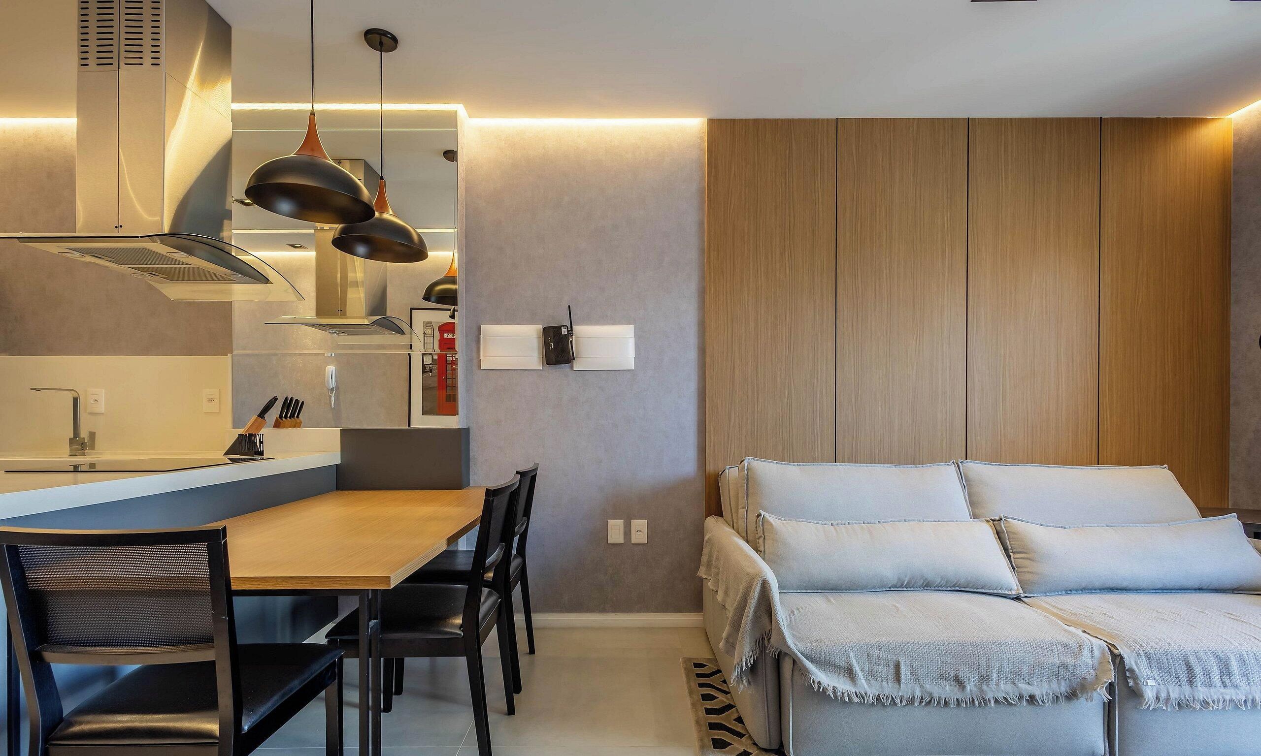 Une cuisine moderne avec un coin repas, des meubles en bois et un canapé avec des coussins.
