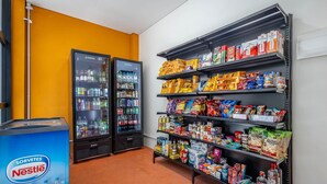 Mostrador refrigerado con bebidas, un enfriador Nestlé y estantes llenos de aperitivos y productos envasados.