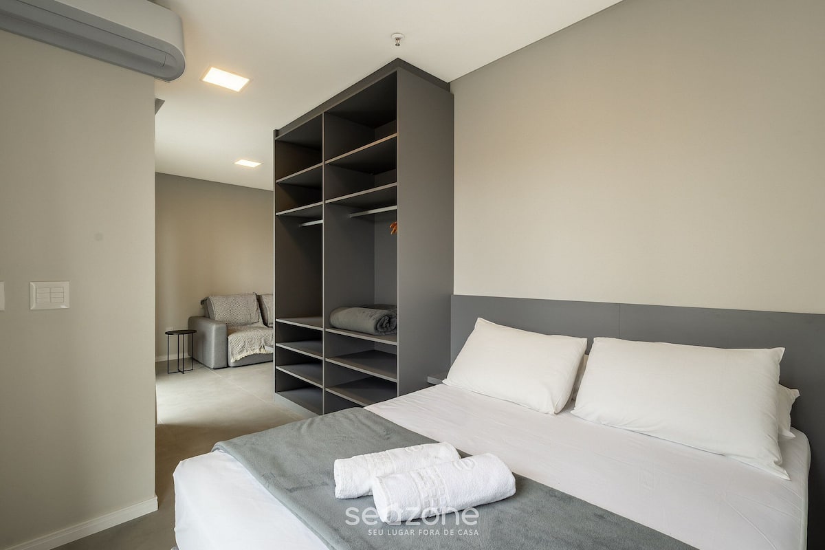 Une chambre à coucher moderne avec un grand lit, une tête de lit grise et une armoire intégrée.