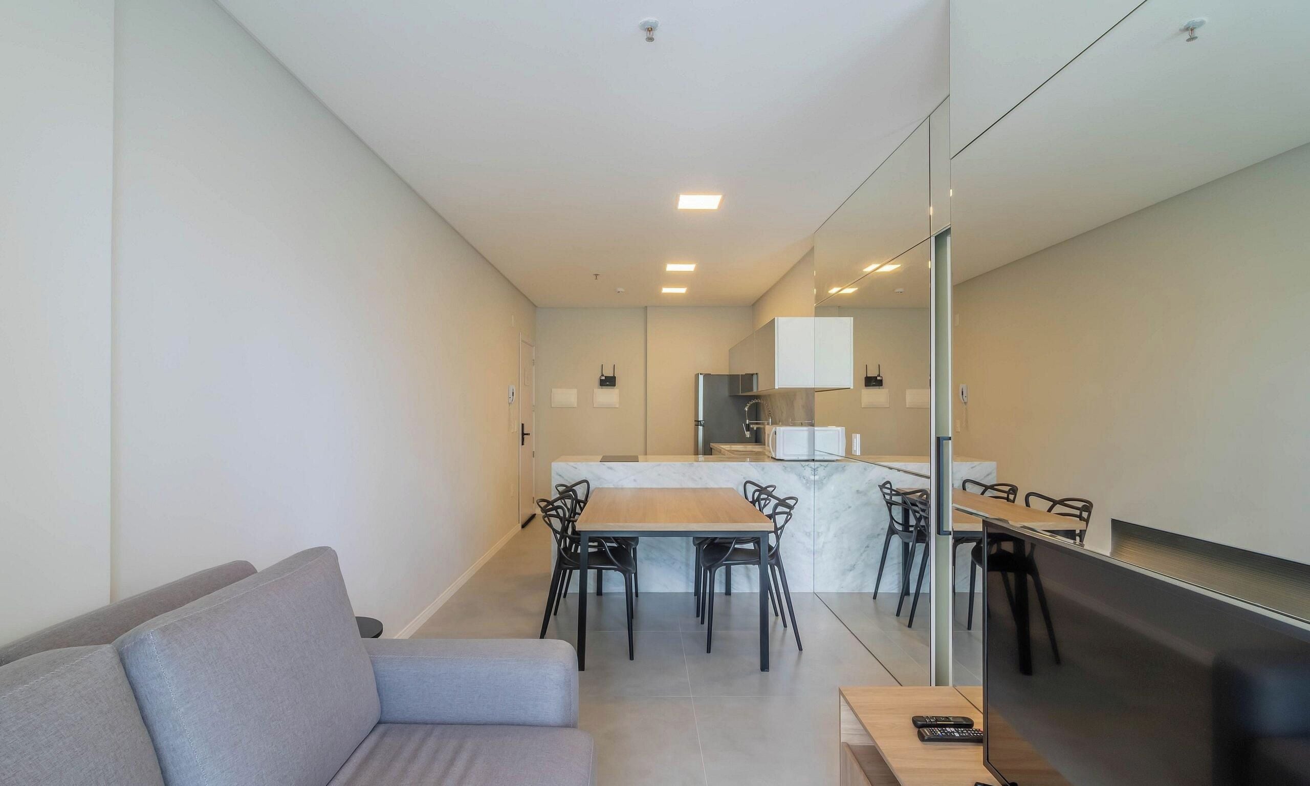 Un salon moderne comprenant un canapé, une table à manger avec des chaises, un coin cuisine avec des placards et un téléviseur.