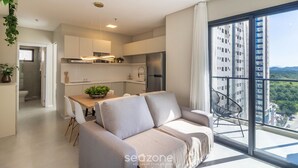 Un apartamento moderno con sala de estar, cocina y balcón con vista a la ciudad.