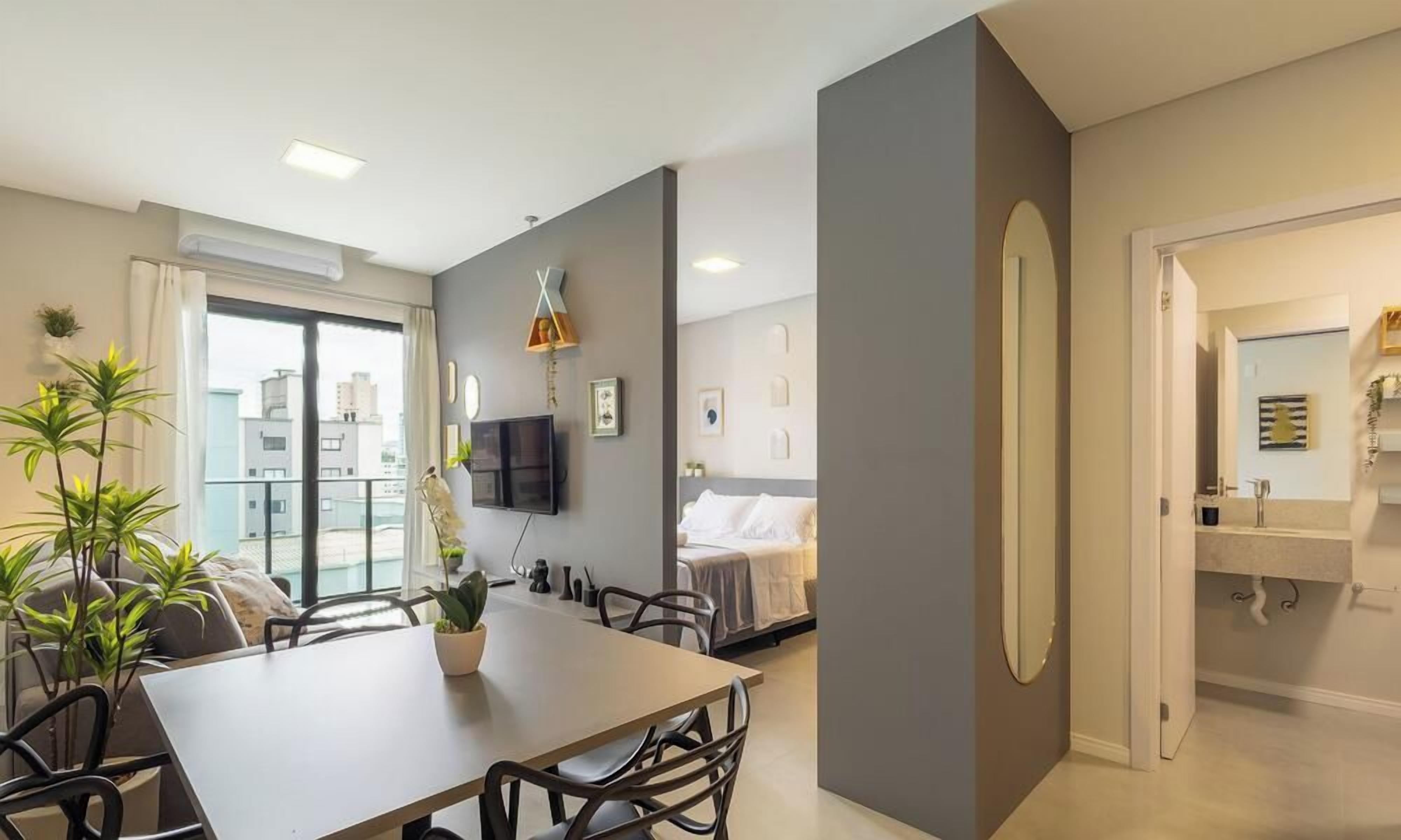 A modern living room with a dining area, a TV, and a bed.