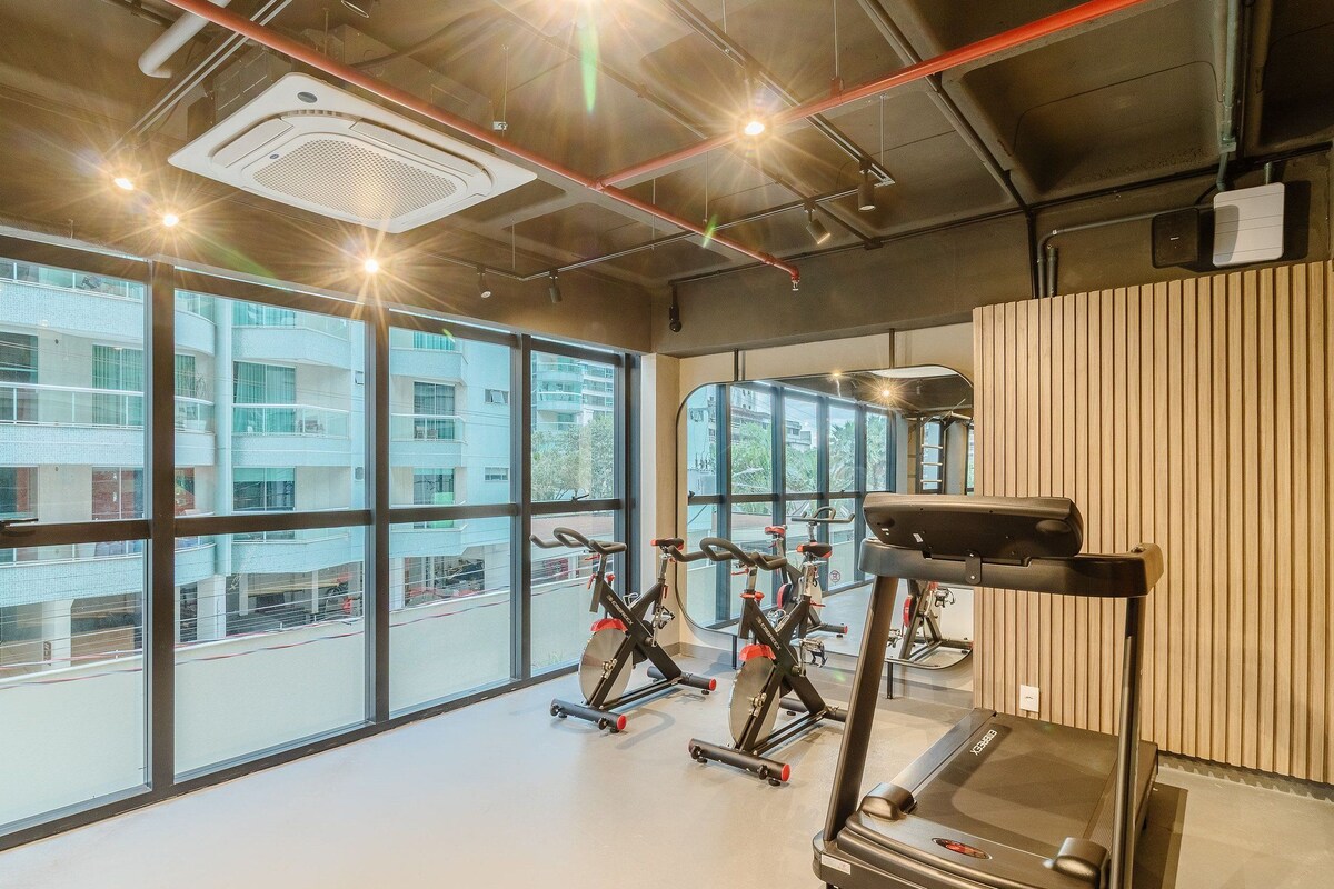 Ein Fitnessstudio mit Trainingsgeräten, großen Fenstern und Blick auf ein Gebäude.