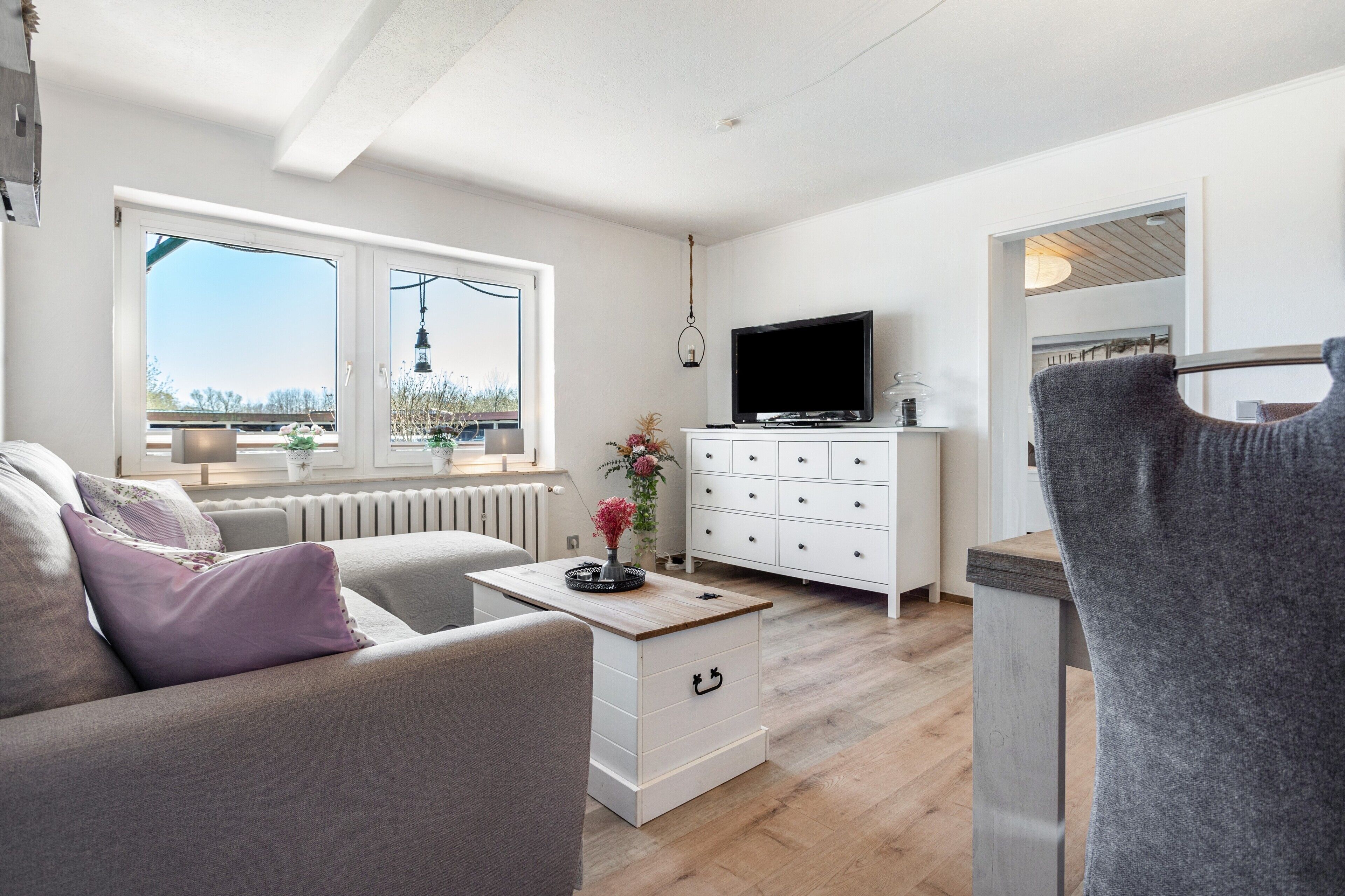 Ein modernes Wohnzimmer mit einer Couch, einem Couchtisch, einem Fernseher und einer weißen Kommode.