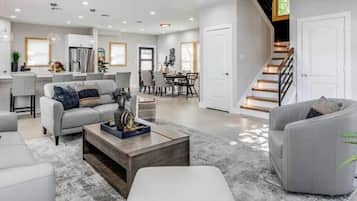 A spacious living area with a gray sofa, a wooden coffee table, and a dining area in the background.
