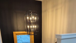 Un escalier avec un mur noir, une fenêtre à cadre en bois et un luminaire moderne.