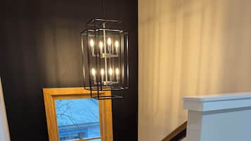 A staircase with a black wall, a wooden-framed window, and a modern light fixture.
