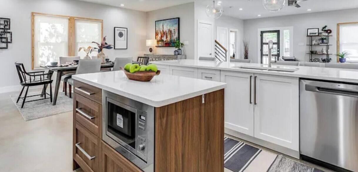 A modern kitchen with a central island, built-in oven, and stainless steel appliances.